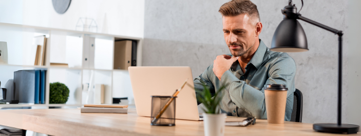 Skupiony mężczyzna pracujący przy laptopie w nowoczesnym biurze